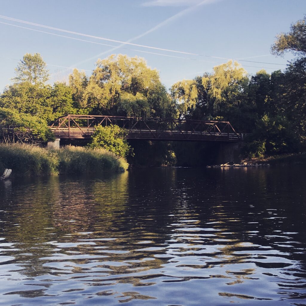 The Grafton Interurban Bridge offers a scenic view of a modern steel truss bridge spanning the waterway. The bridge is part of the Ozaukee Interurban Trail, connecting the trail's path across the Milwaukee River.